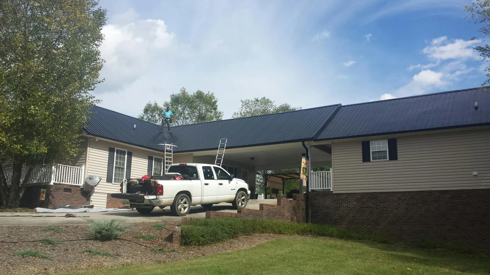 Black metal roof over a home and attached breezeway with ladders set in Hanover